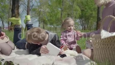 十几岁的金发男<strong>孩</strong>躺在公园的毯子上看书，可爱的小女<strong>孩</strong>穿着粉红色的裙子坐在附近。 <strong>二</strong>.